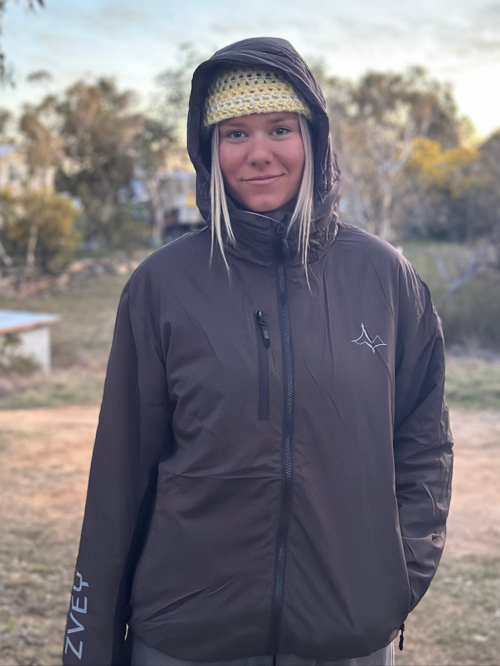 Person wearing a dark jacket with a hood in an outdoor setting